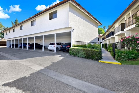 A white building with a red tile roof and a parking lot in front.