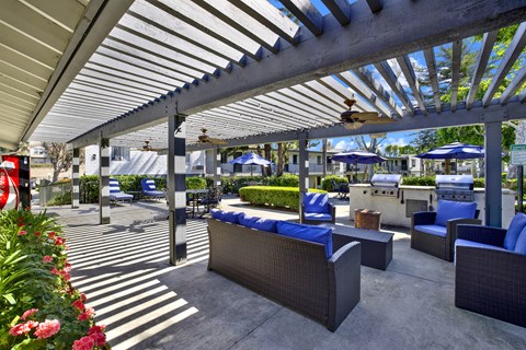 A patio with a white roof and blue chairs.