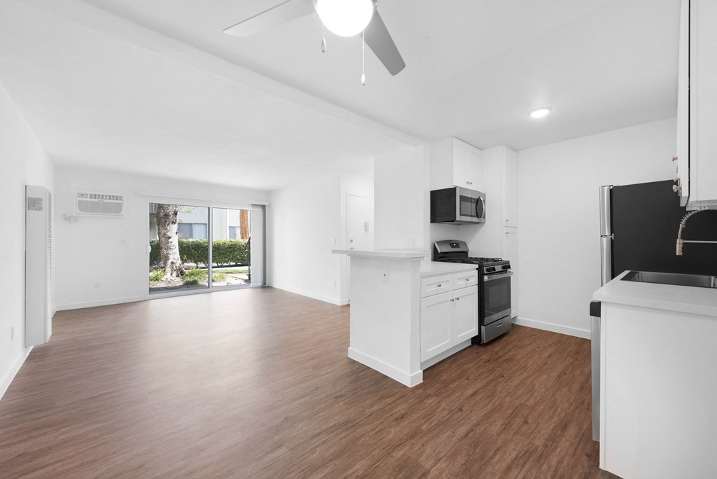 a kitchen and living room with hardwood floors and white walls