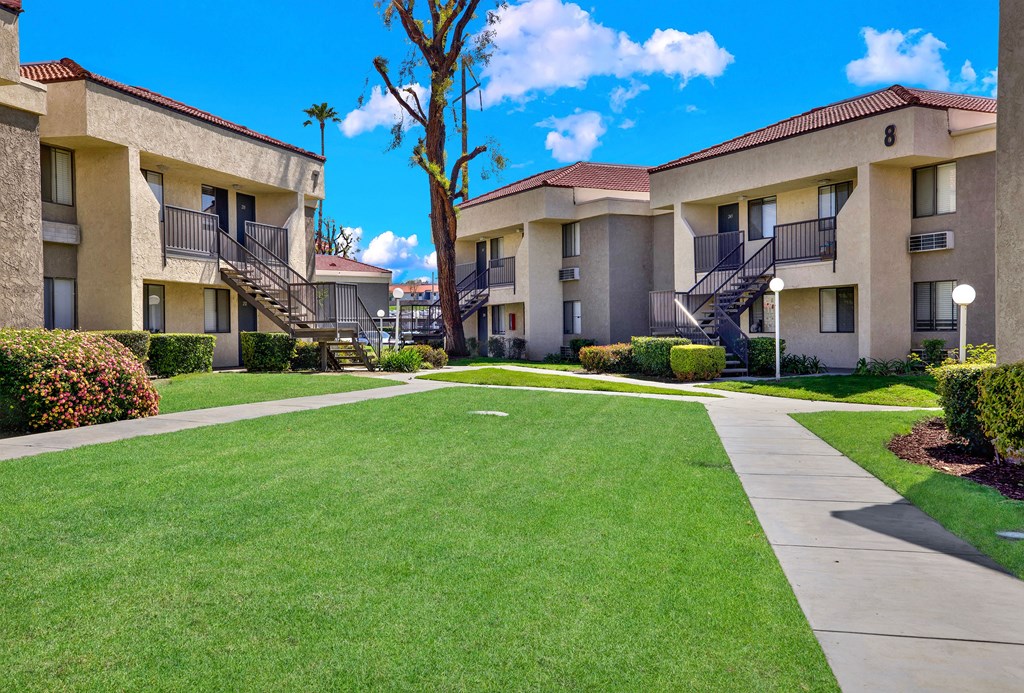 A sunny day at a well-kept apartment complex with green lawns and clear skies.