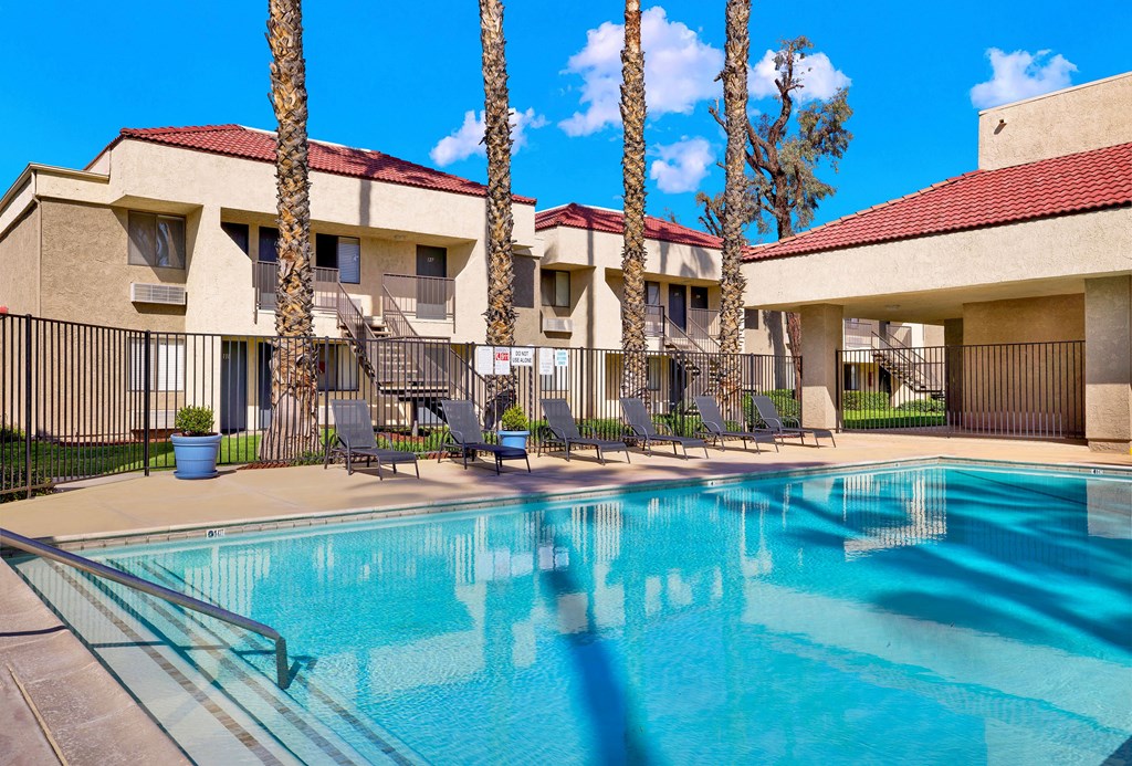 A swimming pool in front of a building with palm trees.