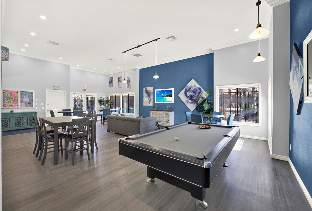 A billiard table is in the middle of a room with a dining table and chairs.