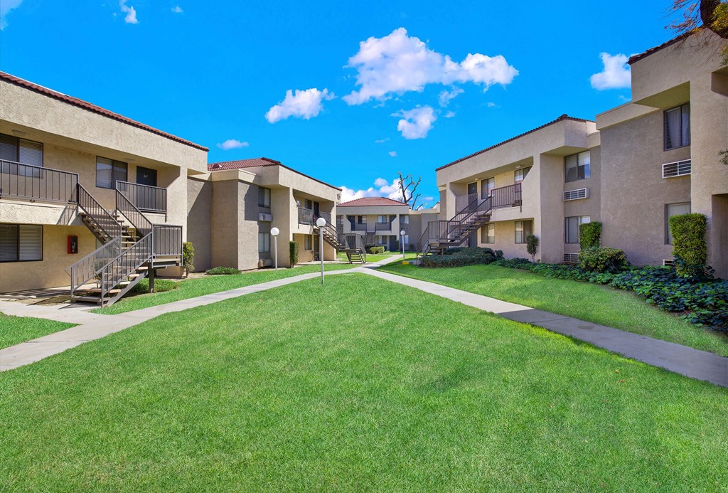 A sunny day at the apartment complex with green lawns and buildings on either side.