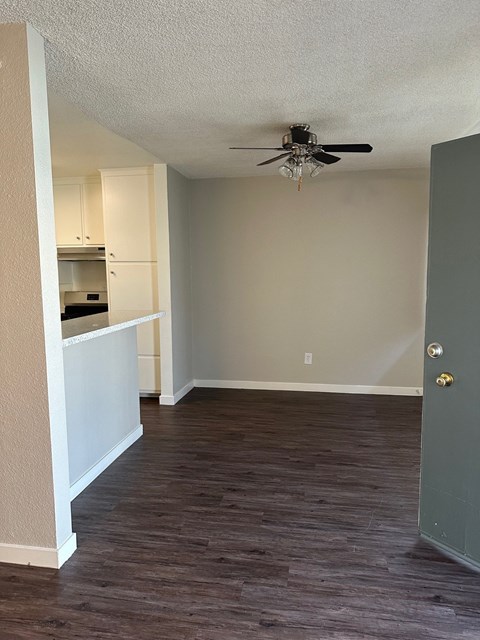 an empty living room with wood floors and a ceiling fan