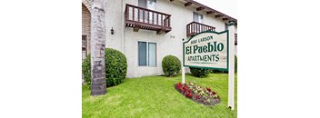 A sign for El Pueblo Apartments stands in front of a building.