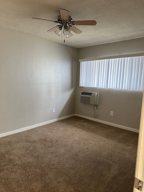 an empty room with a ceiling fan and a window