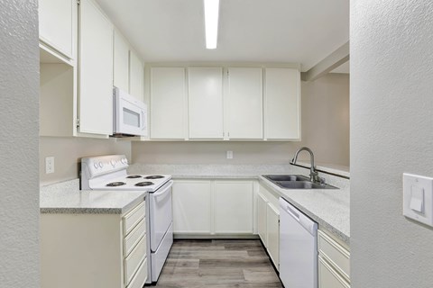 A kitchen with white cabinets and appliances.
