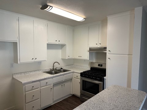 a kitchen with white cabinets and granite counter tops and a stove and sink