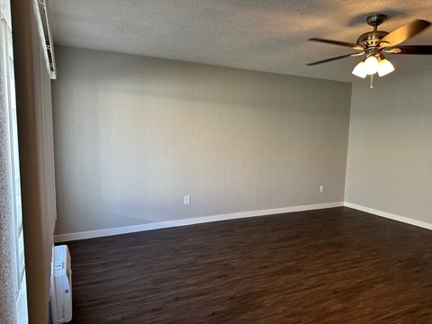 an empty living room with wood floors and a ceiling fan