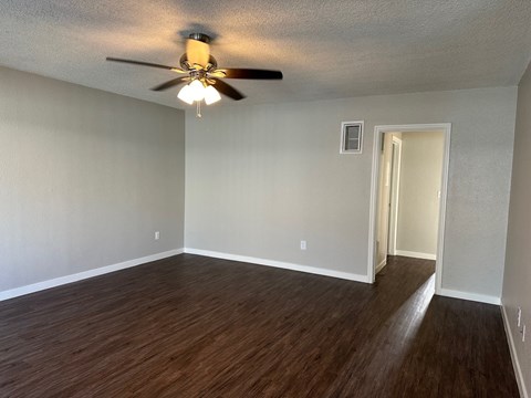 an empty living room with wood floors and a ceiling fan