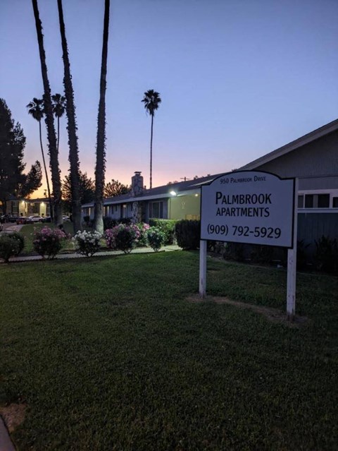 a white sign in the grass in front of a house