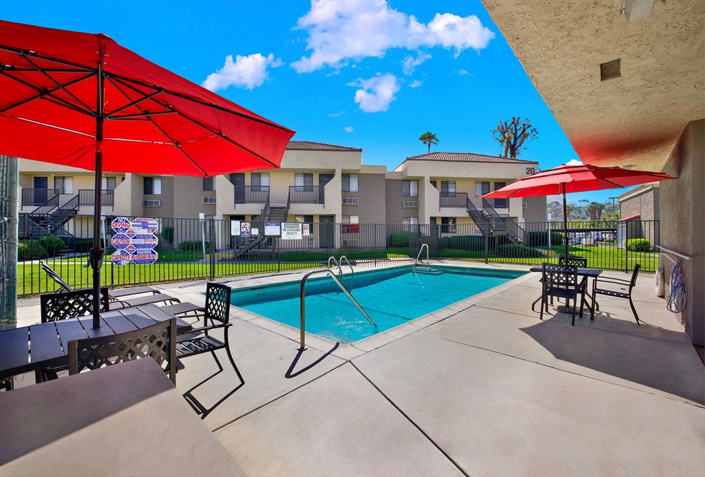 A pool area with red umbrellas and a blue pool.