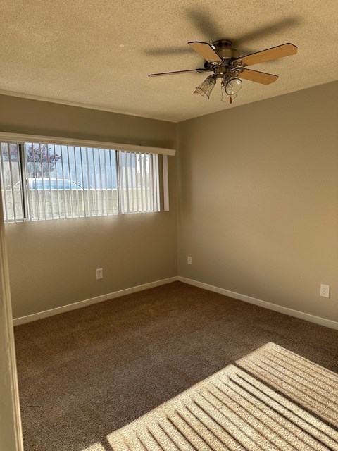 an empty living room with a ceiling fan