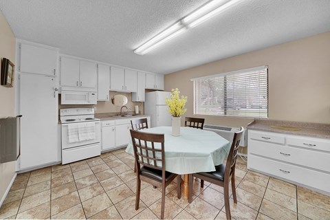 a kitchen with white cabinets and a table with chairs