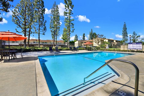 A swimming pool with a blue tinted water and a metal railing.
