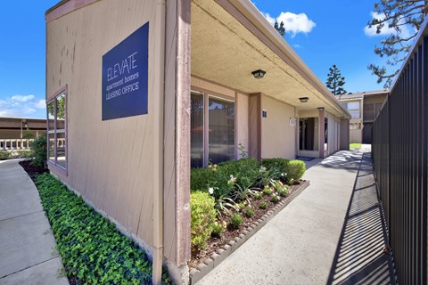 Leasing office entrance with signage and garden at ELEVATE Apartments HOMES, Placentia, 92870