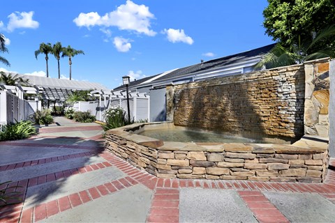 A stone fountain in the middle of a brick walkway.