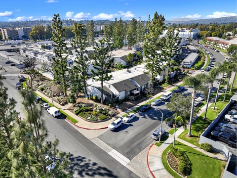 A sunny day in a suburban area with a parking lot and trees at THE STREAMS Apartments, Fullerton, 92831