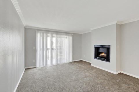 A living room with a fireplace and a window with blinds.