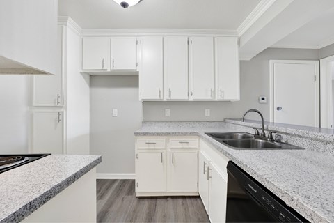 A kitchen with white cabinets and a granite countertop.