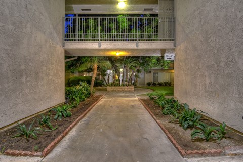 A concrete pathway leads to a balcony with a railing.