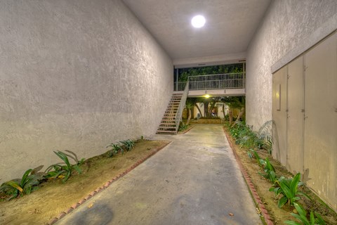 A concrete pathway leads to a staircase in a building.