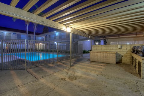 A pool area with a wooden ceiling and a fence around the pool.