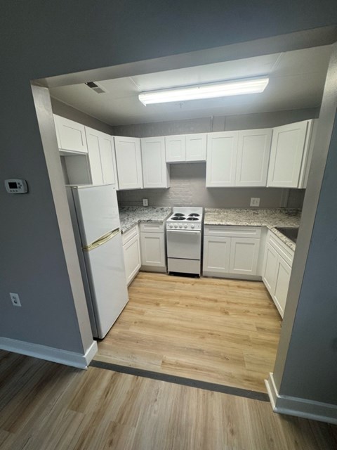 A kitchen with white cabinets and a wooden floor.
