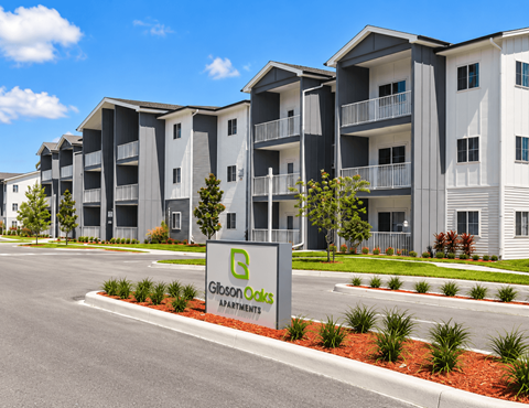 A Gibson Oaks Apartments sign is in front of a building.