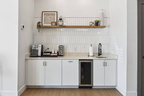A kitchen with white cabinets and a black fridge.