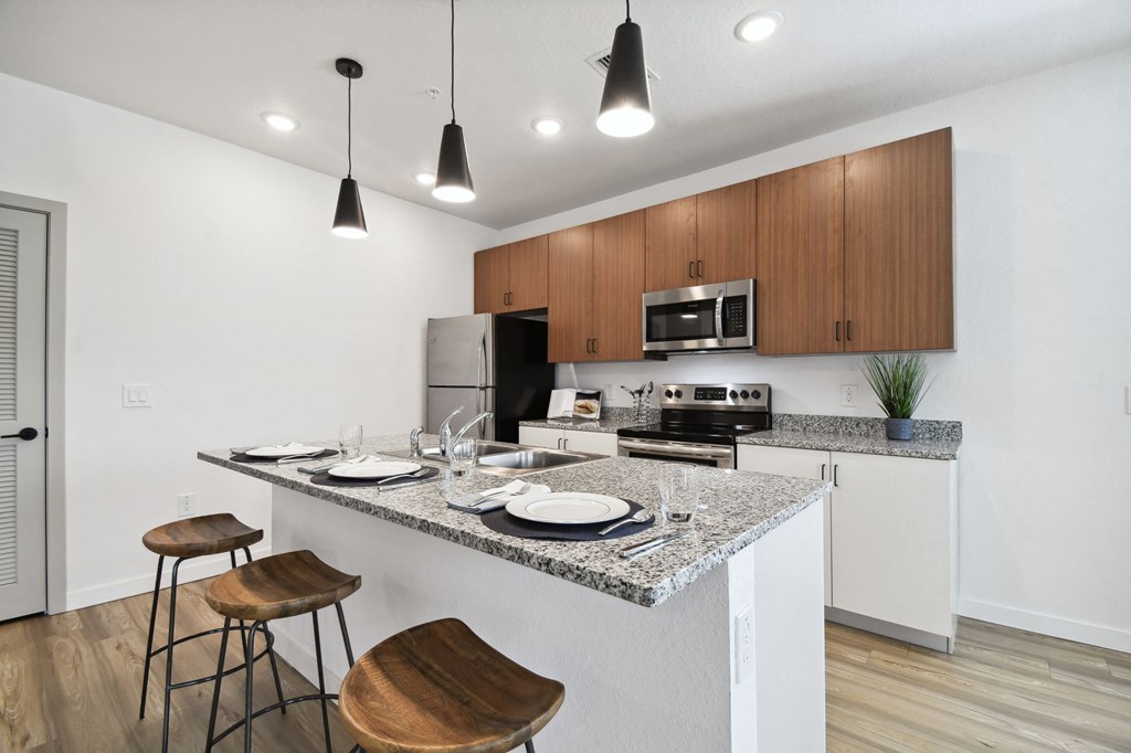 a kitchen with a granite counter at Gibson Oaks, Lakeland, 33809 top and a bar with stools