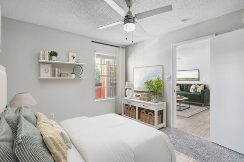 A bedroom with a bed, a ceiling fan, and a window.