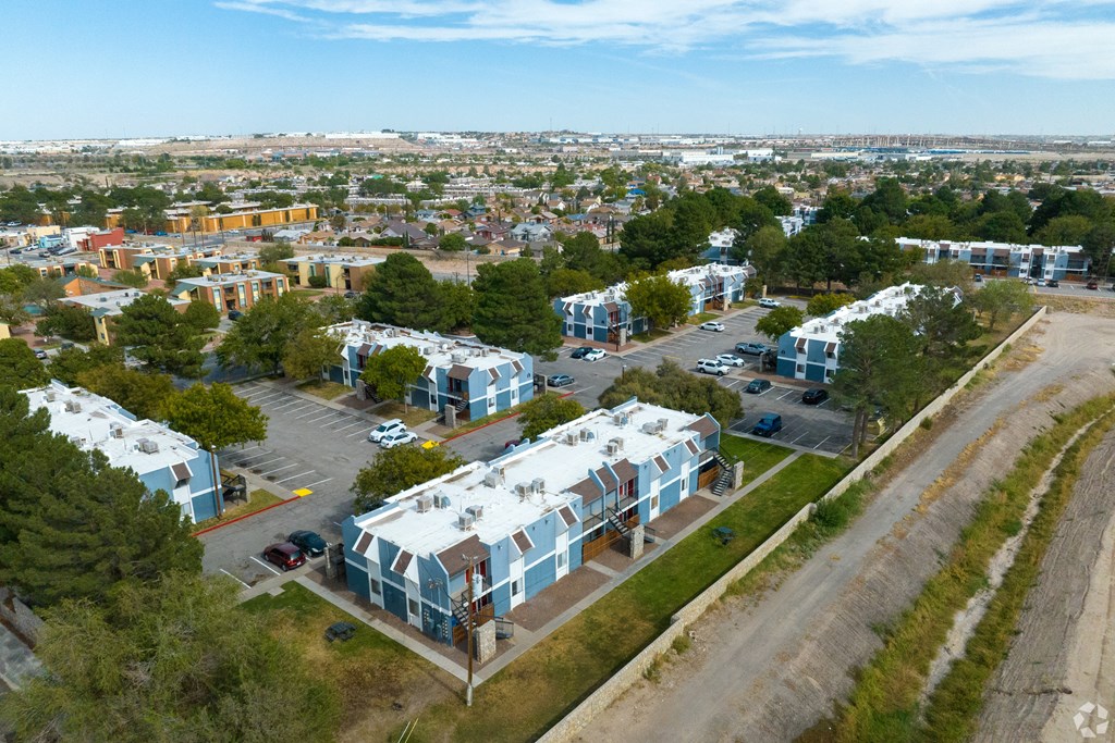 A view of a residential area with apartment buildings and cars parked in the driveways.