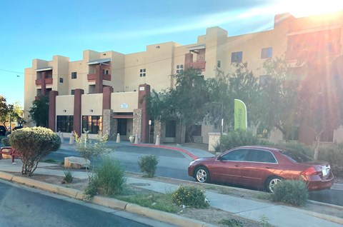 A red car is parked on the side of the road in front of a building.