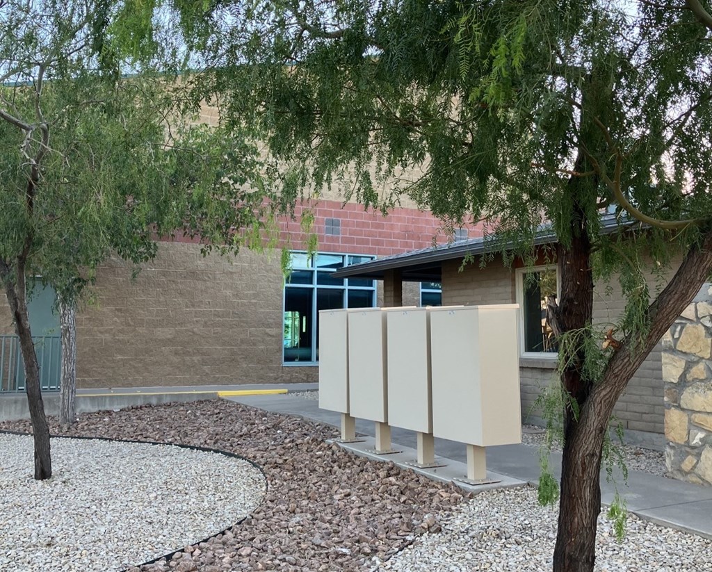 A building with a curved walkway and trees in front.