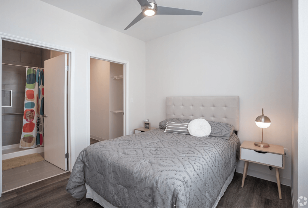 A bedroom with a bed, nightstand, and a ceiling fan.