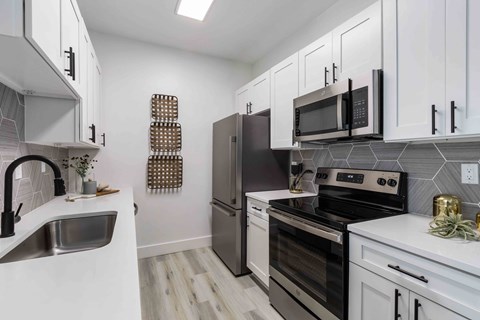 A kitchen with white cabinets and a black fridge.