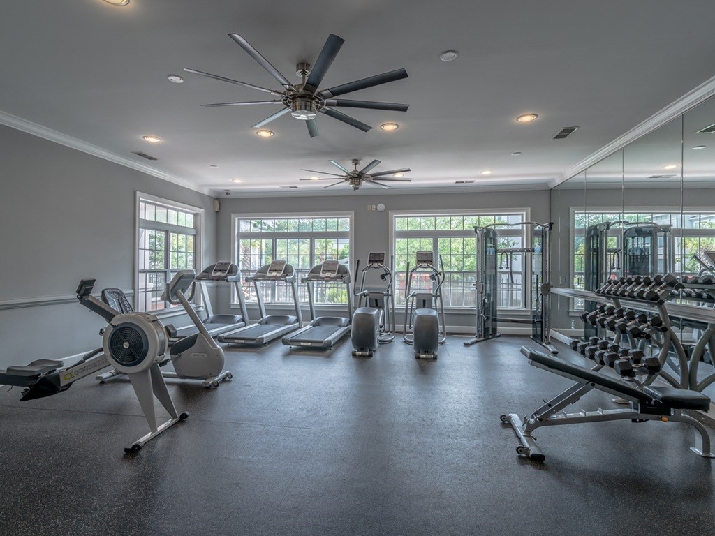 A spacious gym with a variety of equipment and a ceiling fan.