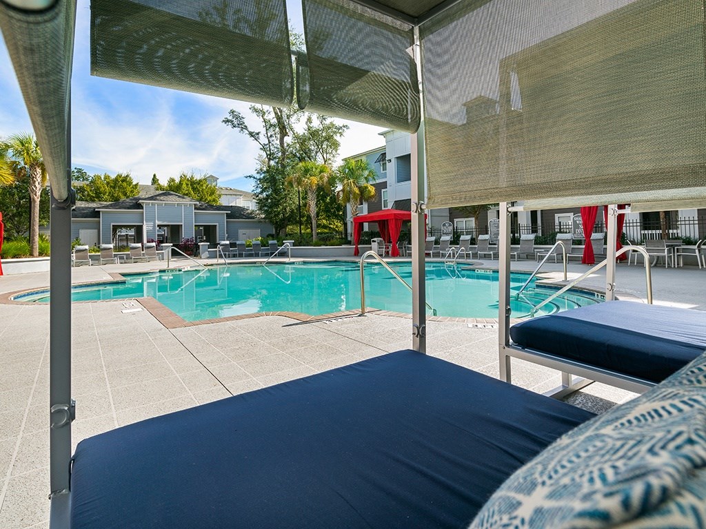 A pool with a blue mattress and a white building in the background.