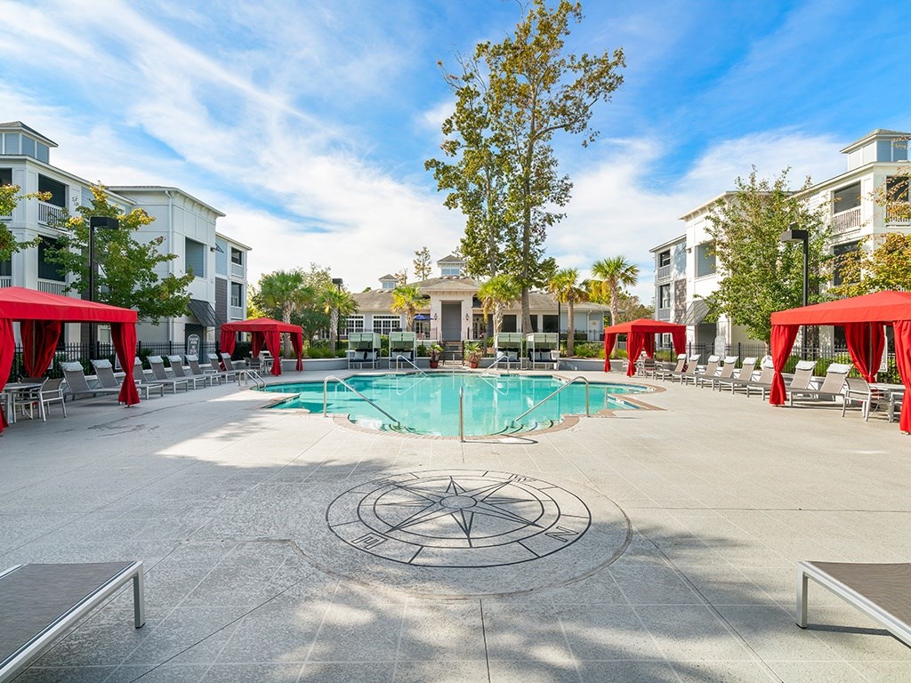 A pool surrounded by red awnings and chairs.