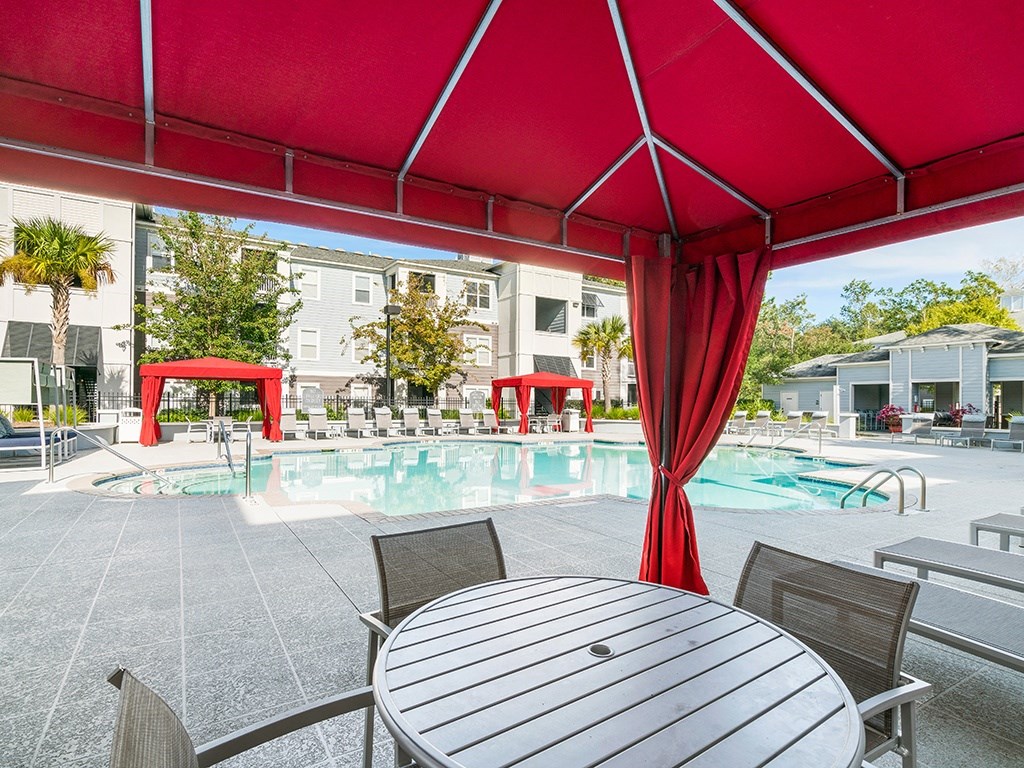A table and chairs are set up under a red canopy.