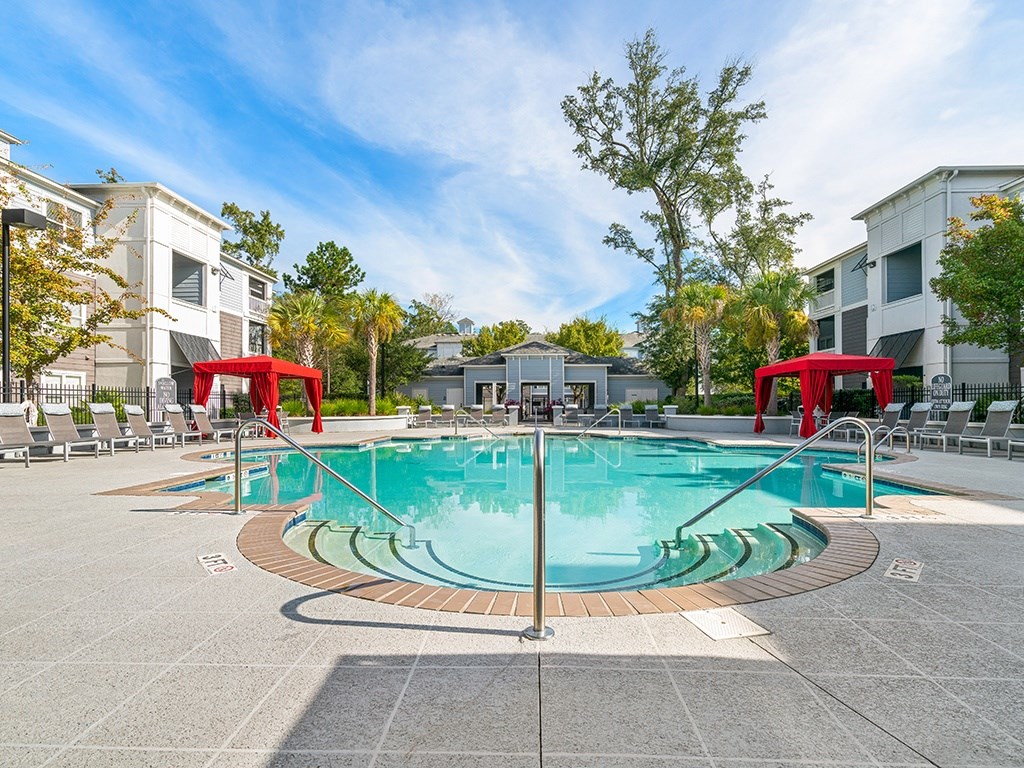 A large outdoor swimming pool surrounded by lounge chairs and umbrellas.