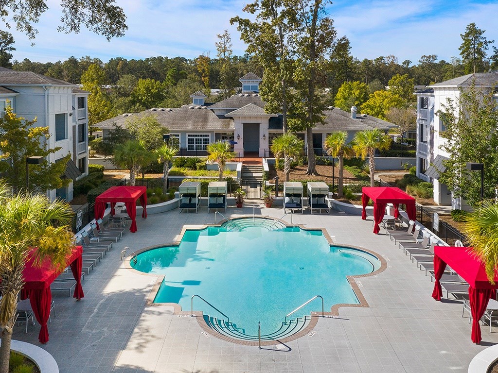 A large swimming pool surrounded by red canopies and lounge chairs.
