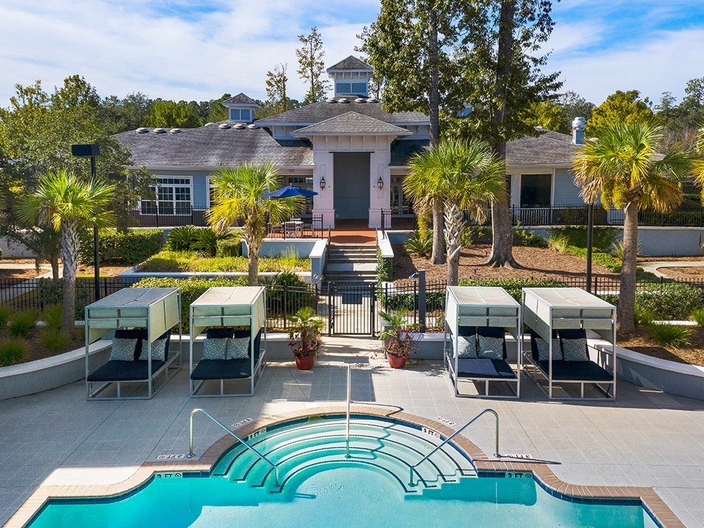 A pool with a slide and sun loungers in front of a house.