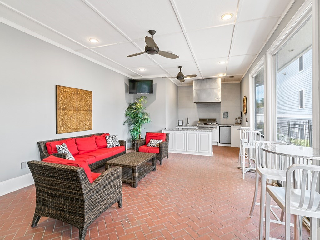 A living room with a red couch and a ceiling fan.