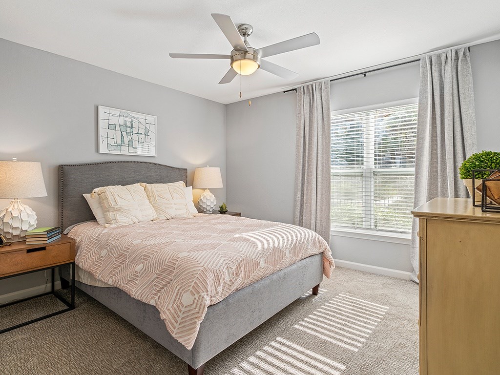 A bedroom with a bed, nightstand, and a ceiling fan.