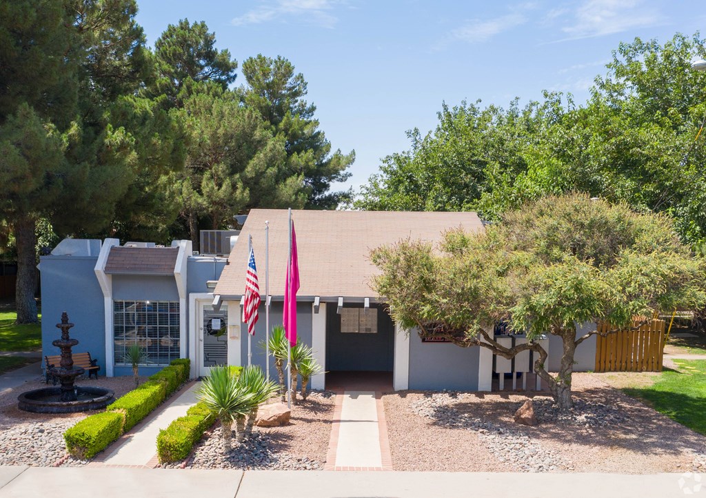A house with a flag and a tree in front.