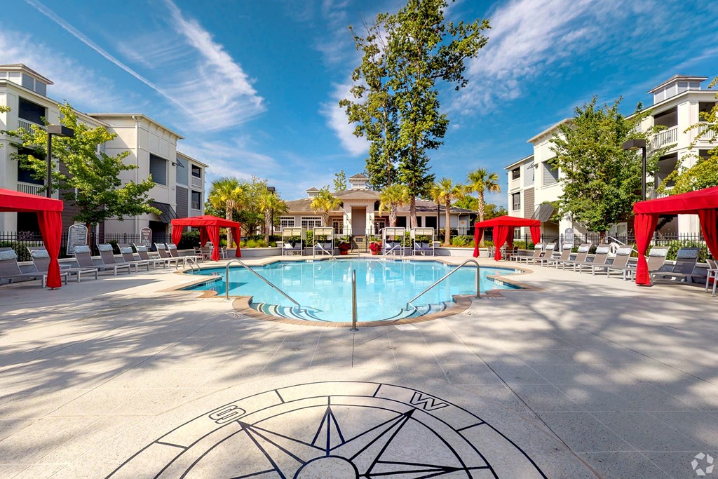 A large swimming pool surrounded by red canopies and lounge chairs.