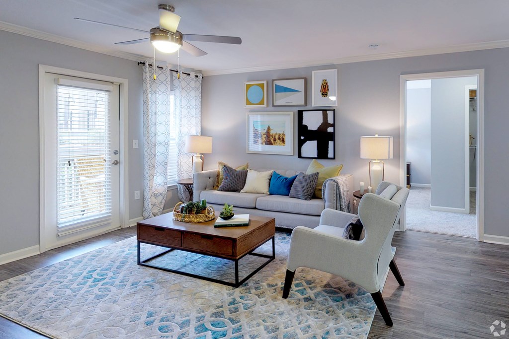 A living room with a grey couch, a wooden coffee table, and a white chair.