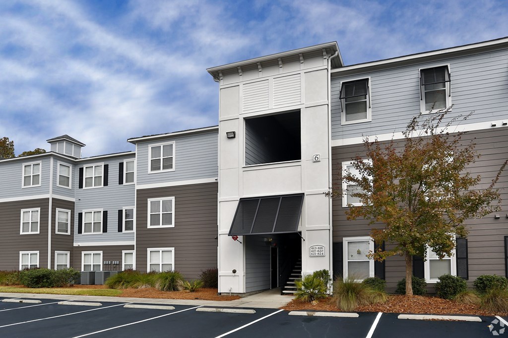 A modern apartment building with a parking lot in front.